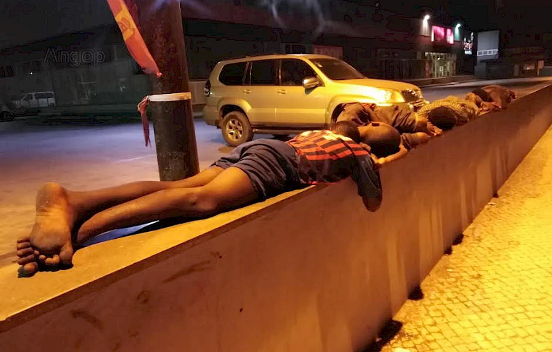 Crianças de rua dormem por cima de um muro